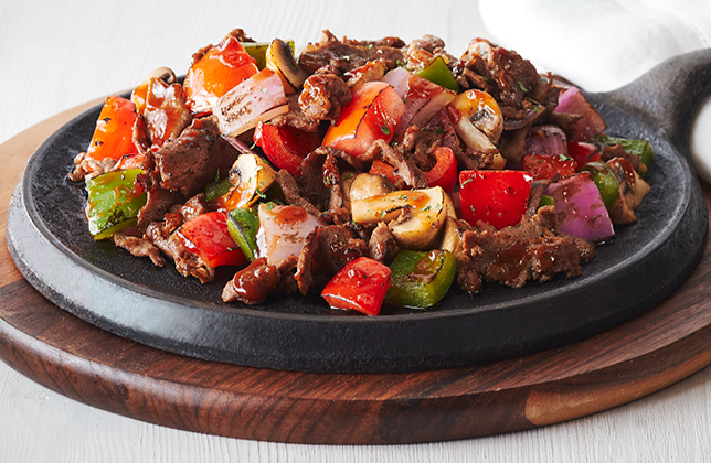 Steak skillet with mushrooms, peppers, tomatoes, onions, garlic butter and BBQ sauce