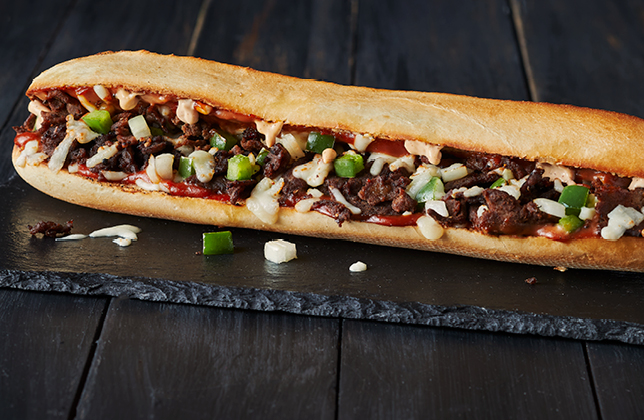 Cheesesteak sandwich with steak, peppers, onions, mozzarella, BBQ sauce and chipotle mayo