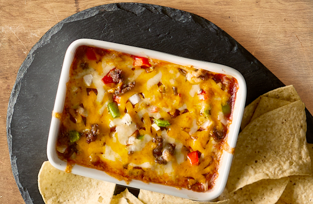 Warm nacho dip with cream cheese, ground beef, salsa, peppers, onions and Tex-Mex cheese